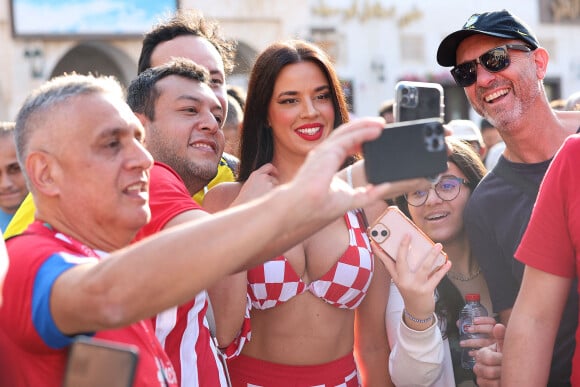 Ivana Knöll, la sulfureuse supportrice croate pose avec ses fans à Doha lors du Mondial 2022 au Qatar le 11 décembre 2022. La jeune supportrice croate assiste à toutes les rencontres de son pays et est reconnue dans tous les stades. Même en dehors dans les rues de Doha, elle ne passe plus inaperçue. Ivana Knöll est en train de devenir une star au Qatar. La mannequin croate de 30 ans possède désormais une très grande communauté. Alors qu'elle possédait moins d'un million d'abonnés sur son compte Instagram, avant le début du Mondial, elle est suivie par plus de 2,3 millions de personnes.