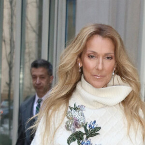 Celine Dion rayonnante et très souriante dans un ensemble pull écru et jupe bouffante fleurie salue ses fans à la sortie de son hôtel à New York, le 8 mars 2020 