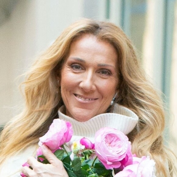 Celine Dion rayonnante et très souriante dans un ensemble pull écru et jupe bouffante fleurie salue ses fans à la sortie de son hôtel à New York, le 8 mars 2020 