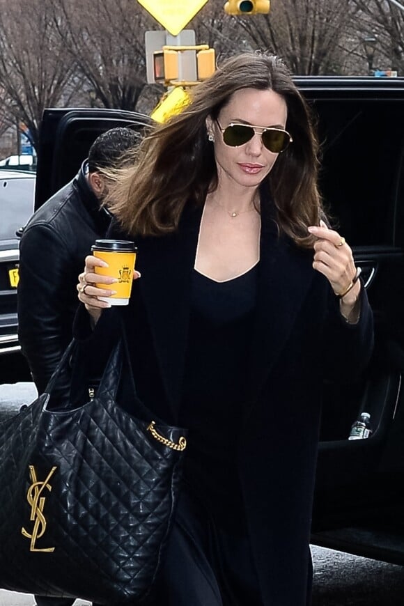 Angelina Jolie se dirige vers un centre d'art à New York City, New York, Etats-Unis, le 12 janvier 2023, avec un café à emporté de chez Carlyle. L'actrice américaine portait une tenue entièrement noire avec un grand sac matelassé YSL. 