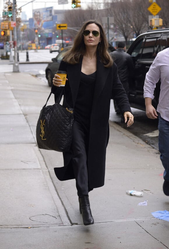 Angelina Jolie se dirige vers un centre d'art à New York City, New York, Etats-Unis, le 12 janvier 2023, avec un café à emporté de chez Carlyle. L'actrice américaine portait une tenue entièrement noire avec un grand sac matelassé YSL. 