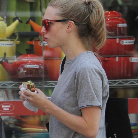 Amanda Seyfried mange un sandwich en marchant dans le quartier de Union Square à New York, le 12 août 2015.