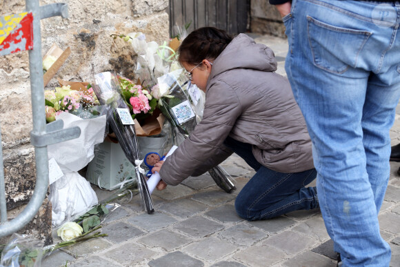 Une petite fille dépose un bouquet de fleurs au pied de l'église - Funérailles de la petite Lola en la collégiale Saint-Omer de Lillers, dans le nord de la France, le 24 octobre 2022. 