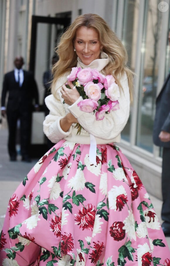 Celine Dion rayonnante et très souriante dans un ensemble pull écru et jupe bouffante fleurie salue ses fans à la sortie de son hôtel à New York, le 8 mars 2020 