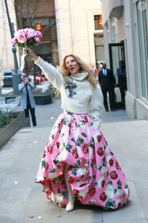 Celine Dion rayonnante et très souriante dans un ensemble pull écru et jupe bouffante fleurie salue ses fans à la sortie de son hôtel à New York, le 8 mars 2020 