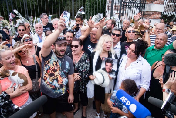 Les fans rendent hommage à Alain Delon à 17 heures en chantant la chanson "Paroles Paroles" avec la pluie qui arrive juste à la fin comme un signe devant la propriété de l'acteur au moment de ses obsèques à Douchy-Montcorbon le 24 août 2024. © Baptiste Autissier / Panoramic / Bestimage 