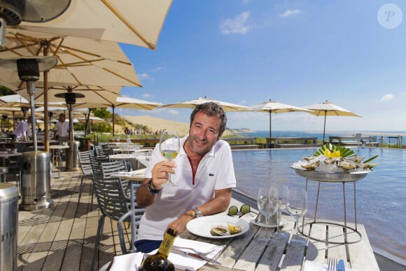 Bernard Montiel, présentateur et animateur radio pose sur la terrasse du restaurant "La Corniche" en dégustant un verre de vin blanc du château Smith Au Lafitte et quelques huïtres. . La Teste-de-Buch Pyla-Sur-Mer, le 14 juillet 2017. © Thibaud Moritz / Bestimage