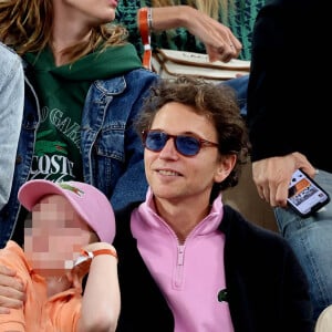 Le chanteur Raphaël, et son fils Aliocha Haroche dans les tribunes des Internationaux de France de tennis de Roland Garros 2024 à Paris, le 29 mai 2024.