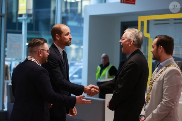 Le prince de Galles est accueilli par la secrétaire d'État à l'Irlande du Nord, Hilary Benn (deuxième à droite), et le maire de Belfast, Micky Murray (à droite), alors qu'il arrive pour une visite au centre du campus de la ville de Belfast de l'université d'Ulster, afin d'entendre parler des travaux qui sont menés pour consolider l'Irlande du Nord en tant que leader mondial de l'excellence créative et de l'innovation, en développant et en perfectionnant la future main-d'oeuvre et en développant les capacités technologiques.