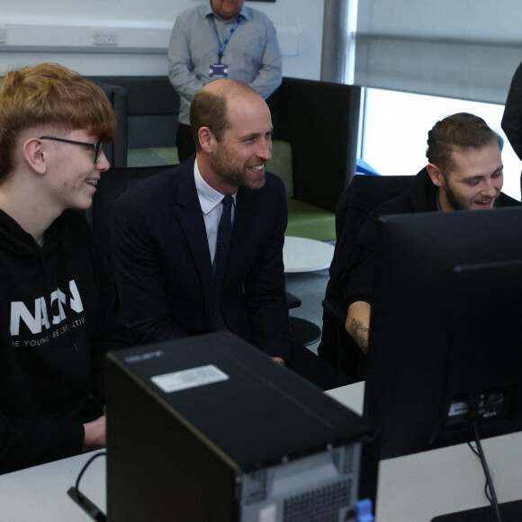 Le prince de Galles (au centre) rencontre un étudiant catholique et un étudiant protestant qui participent à un atelier de formation avec des jeunes des deux communautés à qui l'Ulster Screen Academy apprend à utiliser des logiciels utilisés dans la création de jeux, d'animations et de productions virtuelles, lors d'une visite à l'Ulster University's Belfast City Campus Centre, pour s'informer sur les travaux menés pour consolider l'Irlande du Nord en tant que leader mondial de l'excellence créative et de l'innovation en développant et en perfectionnant la future main-d'oeuvre et en développant les capacités technologiques.