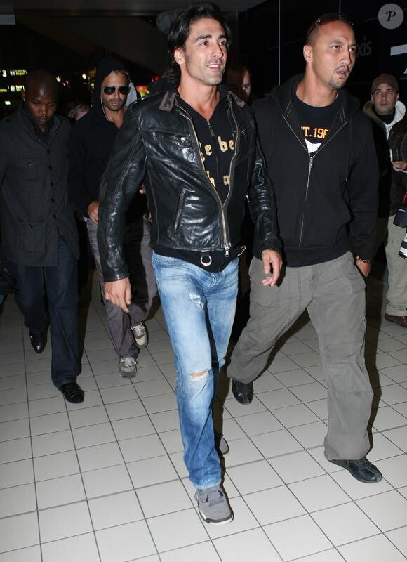 Greg Basso et David Charvet protégés par des gardes du corps à l'aéroport Roissy (9 avril 2010 à Paris)