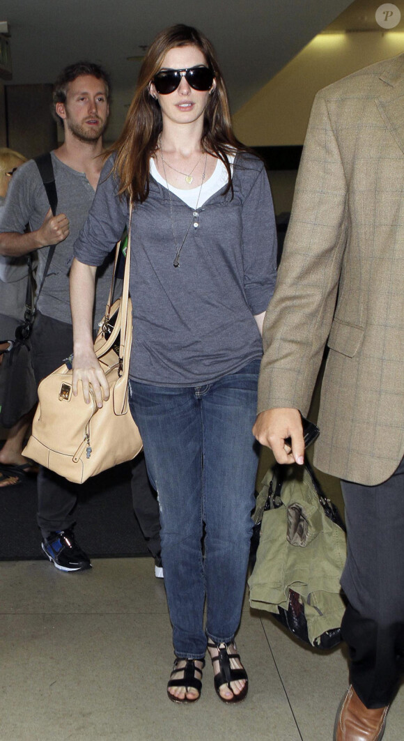 Anne Hathaway et Adam Shulman à l'aéroport de Los Angeles, le 30 mars 2011. Elle ne quitte plus son sac D-Styling de chez Tod's