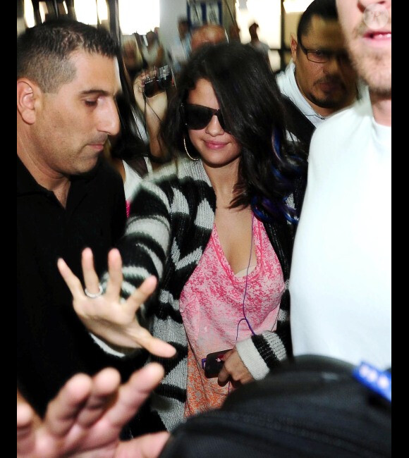 Selena Gomez tente de se frayer un chemin à l'aéroport de Buenos Aires, en Argentine, le vendredi 10 février 2012.