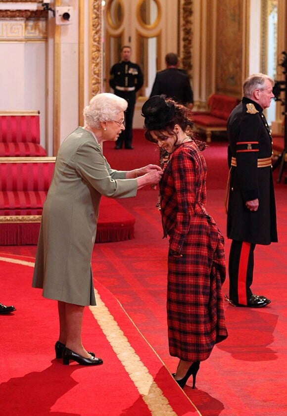 La reine Elizabeth II a remis les insignes de commandeur dans l'ordre de l'empire britannique à Helena Bonham Carter, vêtue d'une robe en tartan signée Vivienne Westwood, le 22 février 2012 à Buckingham Palace.
