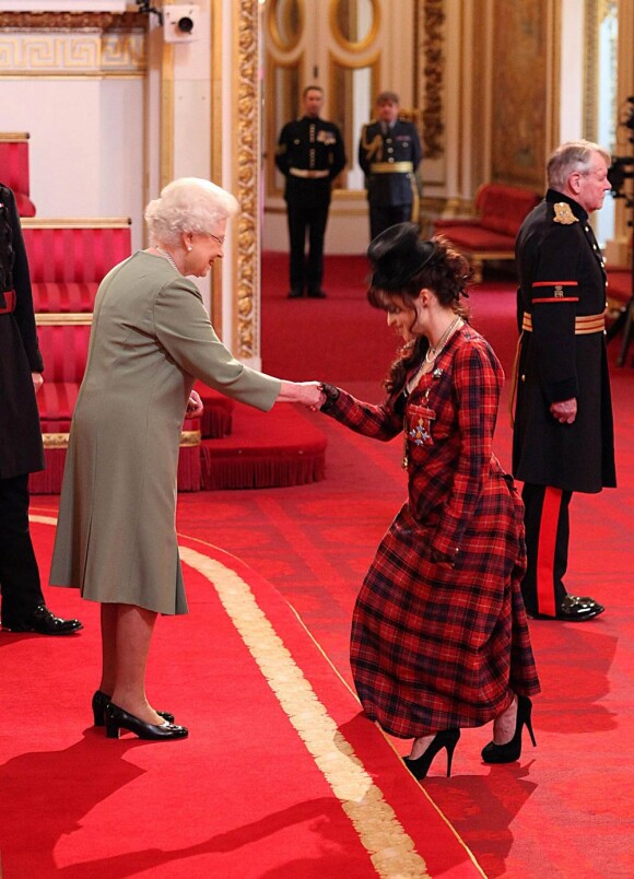 Sa majesté la reine Elizabeth II a remis les insignes de commandeur dans l'ordre de l'empire britannique à Helena Bonham Carter, vêtue d'une robe en tartan signée Vivienne Westwood, le 22 février 2012 à Buckingham Palace.