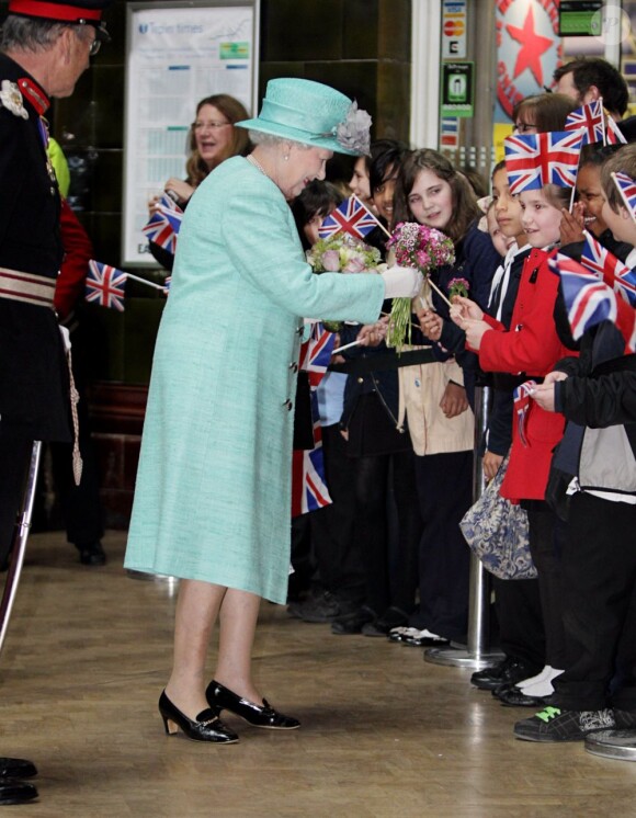 La reine Elizabeth II, habillée d'un chapeau et d'un manteau turquoise, arrive à la gare de Nottingham. Le 13 juin 2012.