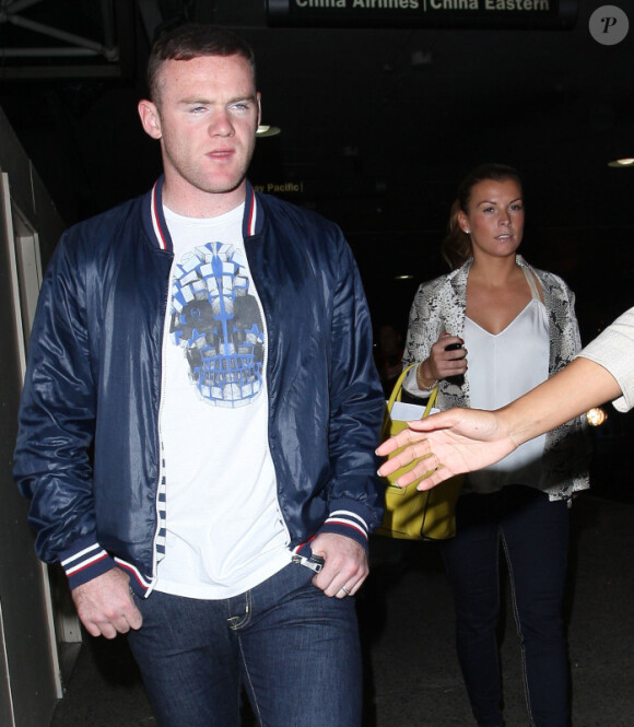 Wayne Rooney, le regard vide, et sa femme Coleen débarquent à Los Angeles le mardi 26 juin 2012