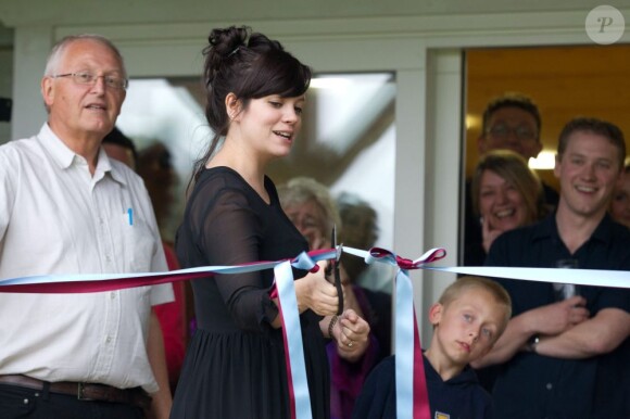 Lily Allen heureuse à l'inauguration d'un club de cricket près de Londres le 8 juillet 2012. La chanteuse porte une robe noire et affiche quelques rondeurs.