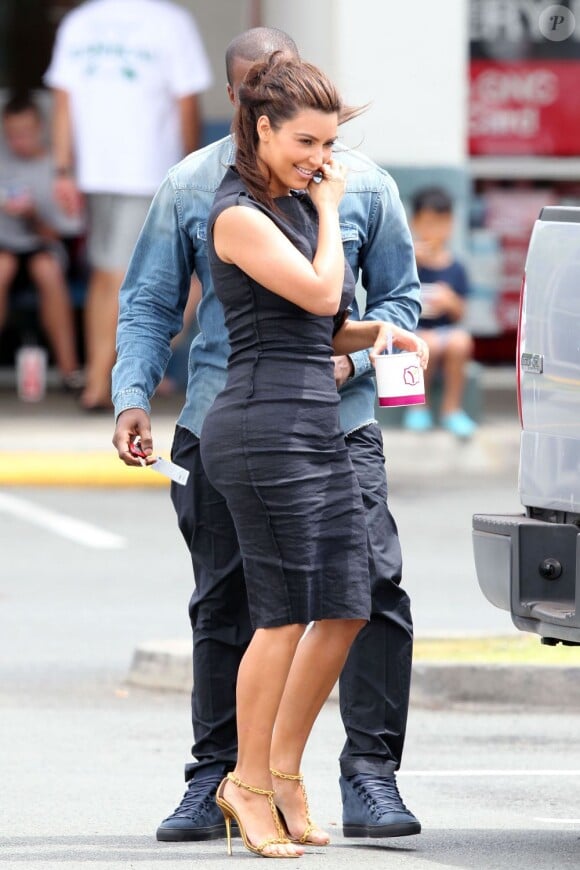 Kanye West en chemise en jean Balmain, pantalon noir et baskets Balenciaga, se cache derrière sa belle Kim Kardashian, ultra sexy dans sa robe noire. Hawaï, le 13 août 2012.