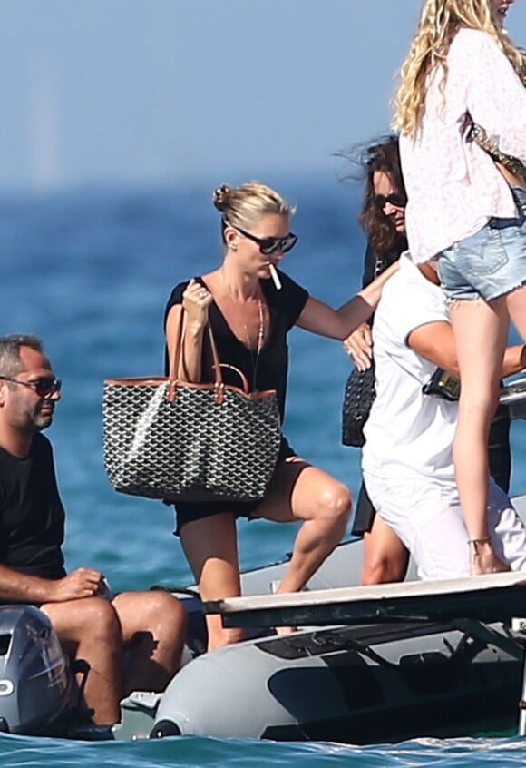 Kate Moss, tenant fermement son sac Goyard, monte en bateau pour mieux profiter du soleil. Saint-Tropez, le 17 août 2012.