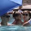 Jennifer Lopez et Casper Smart, dans la piscine avec Emme, tentent de se protéger des photographes à l'aide de parasols. Miami, le 30 août 2012.