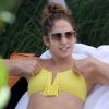 Jennifer Lopez exhibe sa superbe plastique dans un bikini jaune, allongée sur un transat près d'une piscine. Miami, le 30 août 2012.