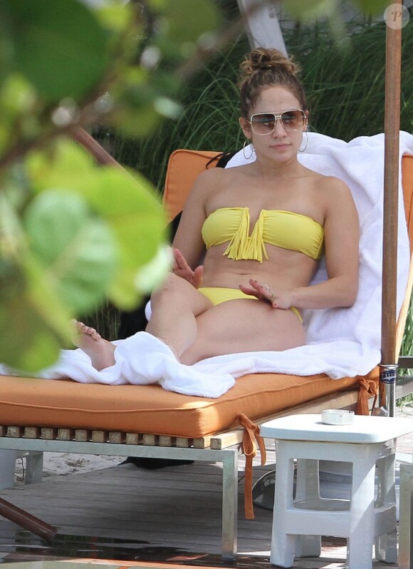 Jennifer Lopez exhibe sa superbe plastique dans un bikini jaune, allongée sur un transat près d'une piscine. Miami, le 30 août 2012.