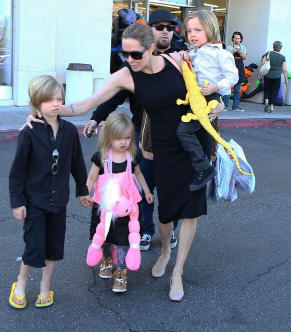 Angelina Jolie emmène trois de ses enfants faire du shopping pour Halloween le 28 octobre 2012 à Sherman Oaks en Californie dans le magasin Party City : elle porte dans ses bras son fils Knox, tandis que Shiloh, l'aînée, tient la main de la petite Vivienne
