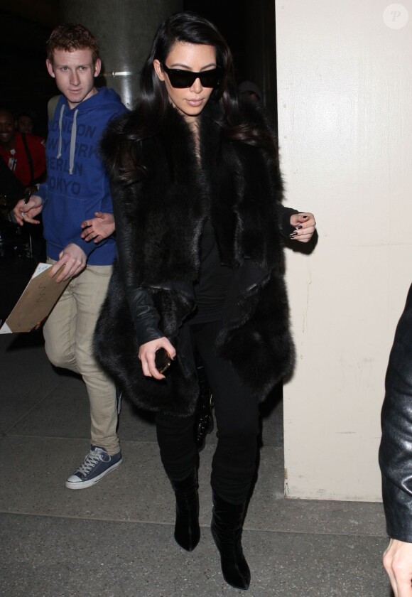 Kim Kardashian, tout de noir vêtue avec des lunettes Céline et un gilet Rick Owens, arrive a l'aéroport de Los Angeles. Le 28 janvier 2013.