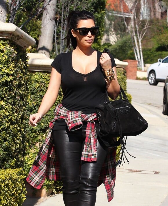 Kim Kardashian, tout de noir vêtue avec une chemise nouée à la taille, quitte son domicile accompagnée de Kanye West et de sa mère Kris Jenner. Los Angeles, le 12 février 2013.