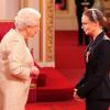 Elizabeth II remettant à Stella McCartney les insignes d'officier de l'ordre de l'empire britannique le 26 mars 2013 à Buckingham.