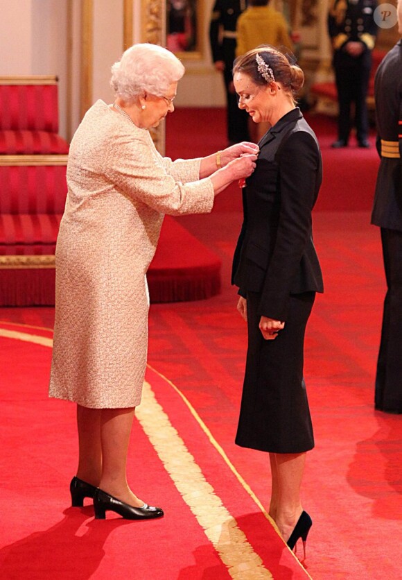 Elizabeth II remettant à Stella McCartney les insignes d'officier de l'ordre de l'empire britannique le 26 mars 2013 à Buckingham.