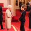 Elizabeth II remettant à Stella McCartney les insignes d'officier de l'ordre de l'empire britannique le 26 mars 2013 à Buckingham.