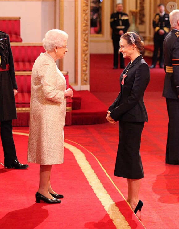 Elizabeth II remettant à Stella McCartney les insignes d'officier de l'ordre de l'empire britannique le 26 mars 2013 à Buckingham.