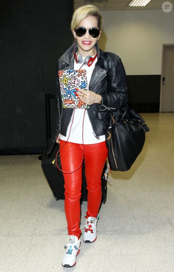 Rita Ora débarque à l'aéroport de Los Angeles, habillée d'un perfecto, d'un pantalon en cuir et de baskets Reebok x Keith Haring assortis à la pochette de son iPad. Le 3 mai 2013.