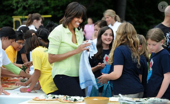 Michelle Obama, toujours aussi souriante, récolte les légumes du potager de la Maison Blanche en compagnie d'enfants originaires du New Jersey qui ont été touchés par l'ouragan Sandy, et ceux qui ont planté les légumes au mois d'avril. Washington, le 28 mai 2013.