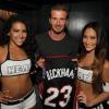 David Beckham au milieu de deux cheerleaders du Heat de Miami, reçoit un maillot à son nom du Heat, lors d'une soirée au Hyde de l'American Airlines Arena après la victoire des locaux face aux Pacers de l'Indiana, le 30 mai 2013, en finale de conférence (90-79)