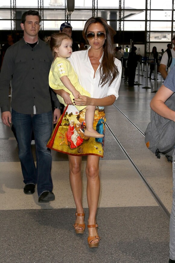 Victoria Beckham, ultrachic en chemise blanche, minijupe Carven (collection automne-hiver 2012) et sandales Chloé à l'aéroport de Los Angeles avec sa fille Harper. Le 1er juin 2013.