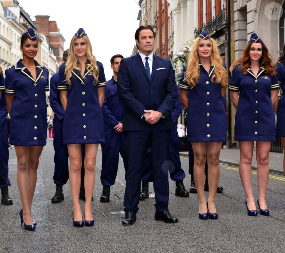 John Travolta, en très charmante compagnie pour l'inauguration de la nouvelle boutique Breitling située au 130 New Bond Street à Londres. Le 27 juin 2013.
