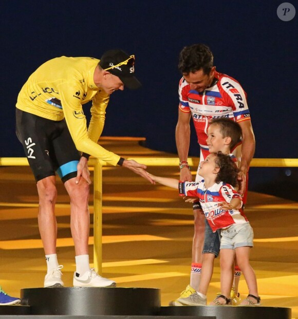 Chris Froome reçoit les félicitations des enfants de Joaquim Rodriguez sur le podium du Tour de France à Paris, le 21 juillet 2013