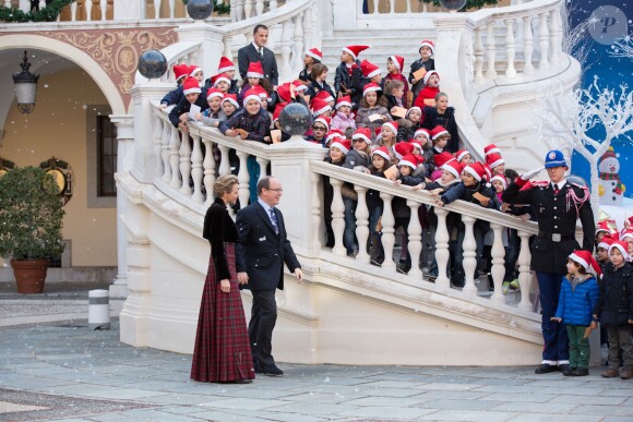 Le prince Albert II de Monaco et la princesse Charlene arrivent sous les yeux de leurs invités lors du goûter de Noël des enfants monégasques dans la cour du palais princier le 18 décembre 2013