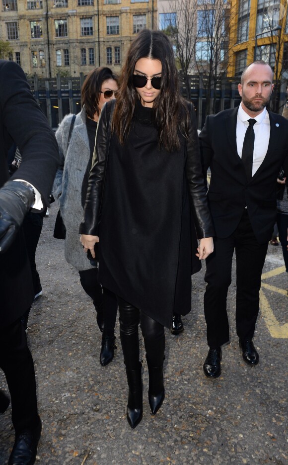 Kendall Jenner, tout de noir vêtue avec un manteau All Saints, un pantalon en cuir et des chaussures Céline, se rend au défilé Topshop Unique. Londres, le 16 février 2014.