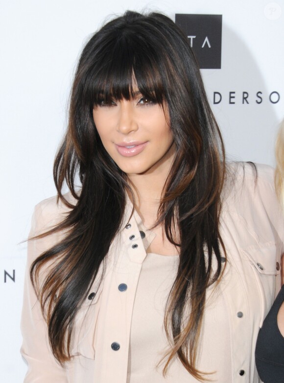 Kim Kardashian glamour avec sa crinière ondulée et sa frange