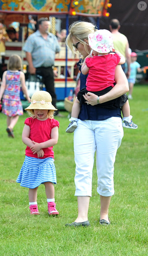 Autumn Phillips avec ses filles Isla, dans ses bras, et Savannah, qui fait un caprice, au Royal Windsor Horse Show le 17 mai 2014.