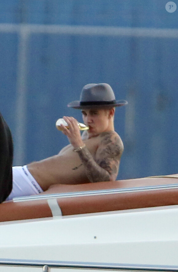 Justin Bieber se relaxe sur un yacht avec des amis à Miami, le 3 juillet 2014. Le jeune chanteur boit une bière assis sur l'avant du bateau.