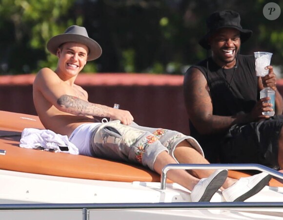 Justin Bieber se relaxe sur un yacht avec des amis à Miami, le 3 juillet 2014. Le jeune chanteur boit une bière assis sur l'avant du bateau. 