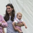 Kate Middleton, la duchesse de Cambridge et son fils George encouragent le prince William et le prince Harry lors du match de polo à Windsor, le 15 juin 2014.