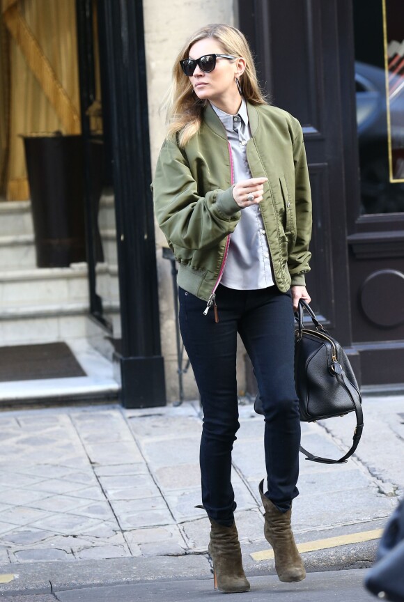 Kate Moss quitte l'hôtel Costes à Paris, habillée d'un bomber réversible kaki et rose, d'une chemise, d'un jean noir rag & bone et de bottines Alaïa. Des lunettes de soleil et un sac Saint Laurent accessoirisent sa tenue. Le 6 novembre 2014.