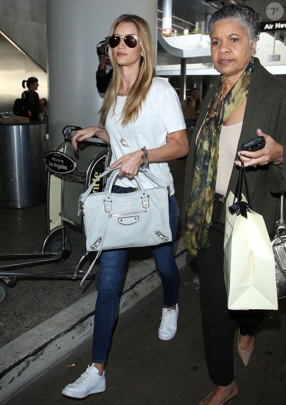 Rosie Huntington-Whiteley à l'aéroport LAX de Los Angeles, porte un t-shirt blanc, un sac Balenciaga blanc, un jean Paige Denim et des baskets Nike (modèle Tennis Classic). Le 14 décembre 2014.