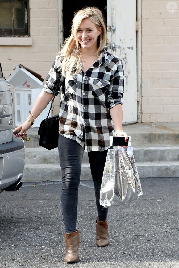 Hilary Duff de sortie à Beverly Hills, Los Angeles, porte une chemise à carreaux, un sac Chanel, un jean noir et des bottines Iro (modèle Kasey). Le 23 décembre 2014.